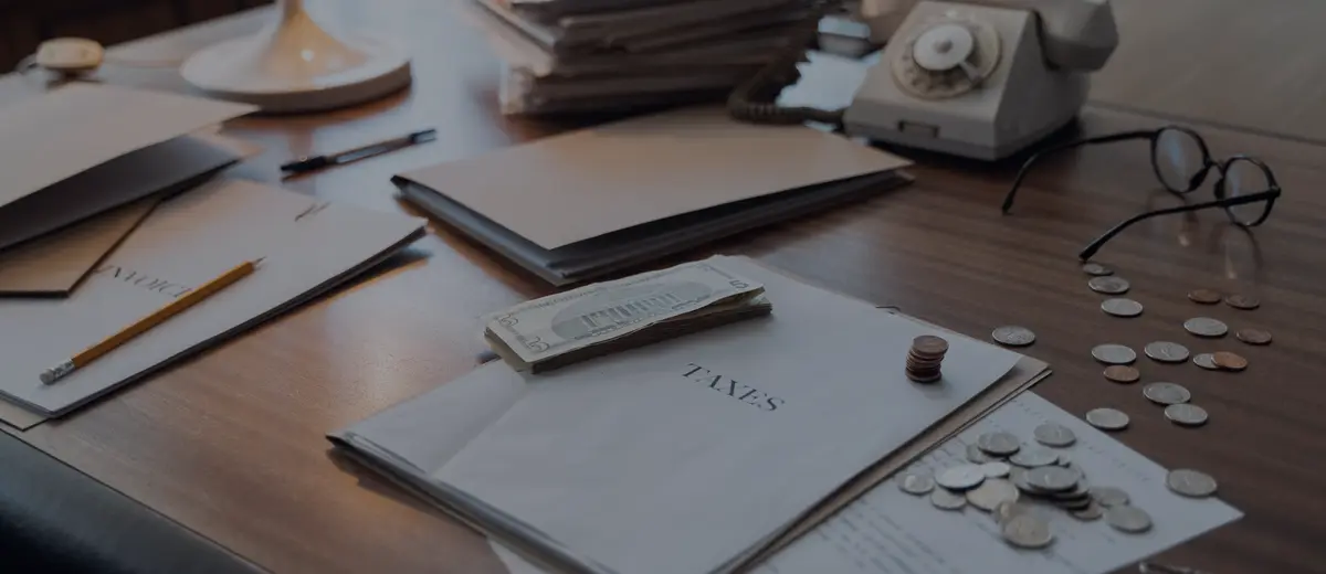 A desk with tax papers, coins and a vintage telephone.