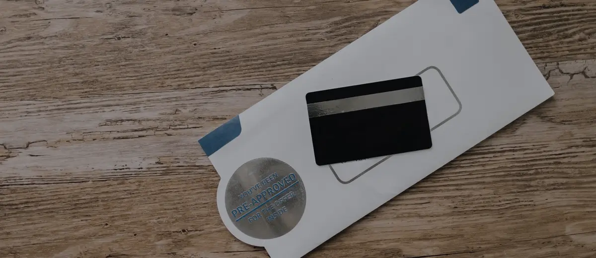 A credit card resting on an envelope on a wooden table.