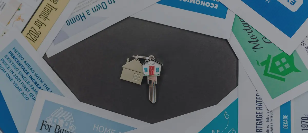 A house-shaped key chain resting on home-buying flyers.