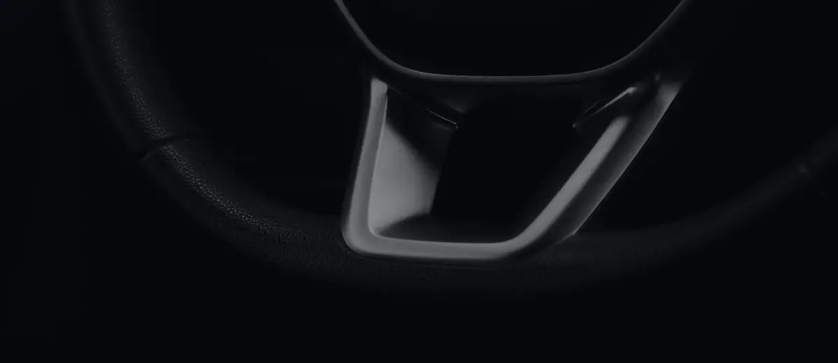 The steering wheel of a new car, close up in low light.