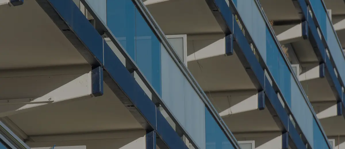Close-up of modern condo balconies with blue glass railings.