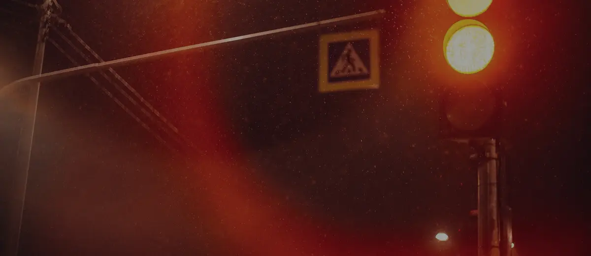 A red traffic light glowing over a foggy street at night.