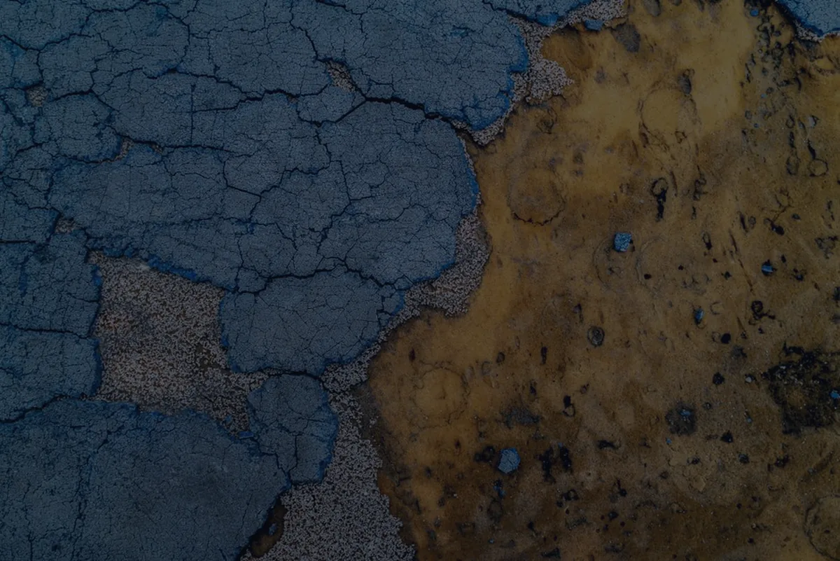 Cracked blue and gold surface texture, representing fund fees quietly eroding investment returns.