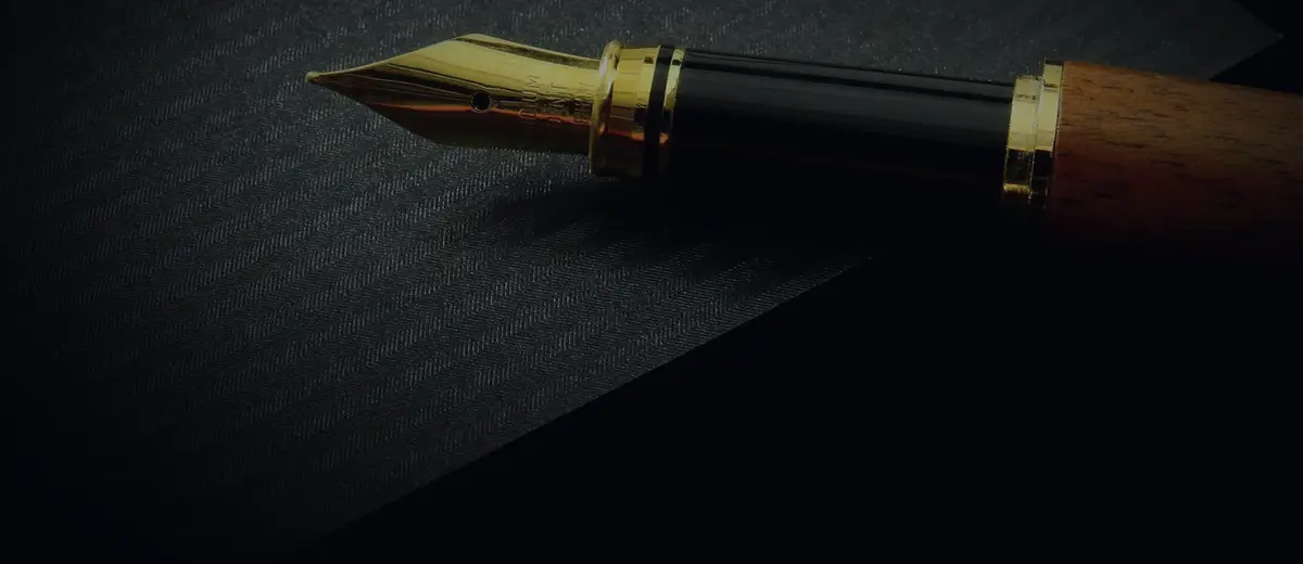A fountain pen nib resting on black paper.