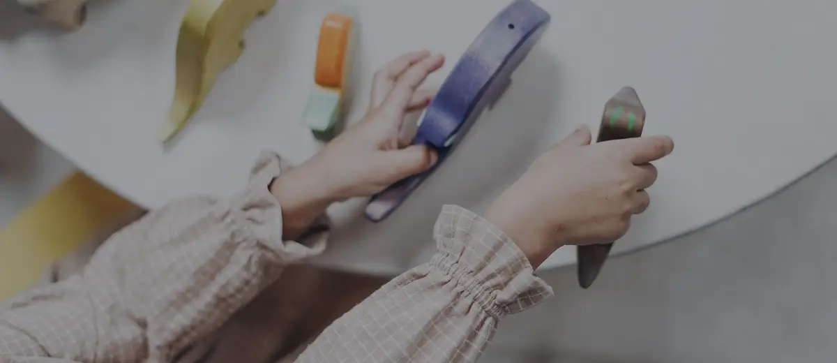 A child's hands playing with colorful toys on a white table.