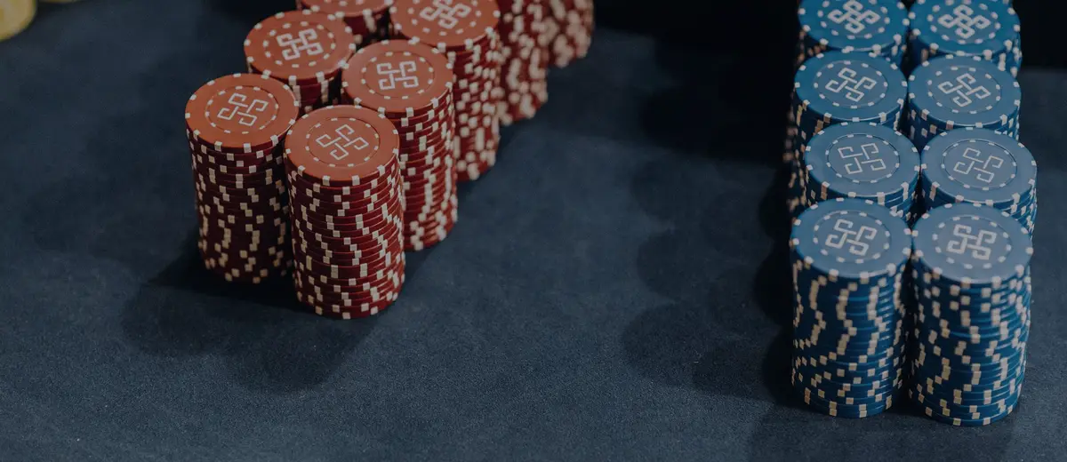 Stacks of red and blue casino chips on a blue felt table.