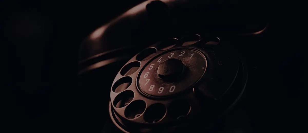 A rotary telephone in deep shadow.