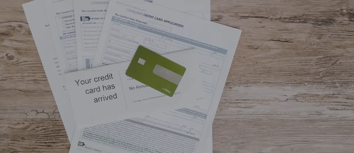 Paper statements and a credit card on a wooden desk.