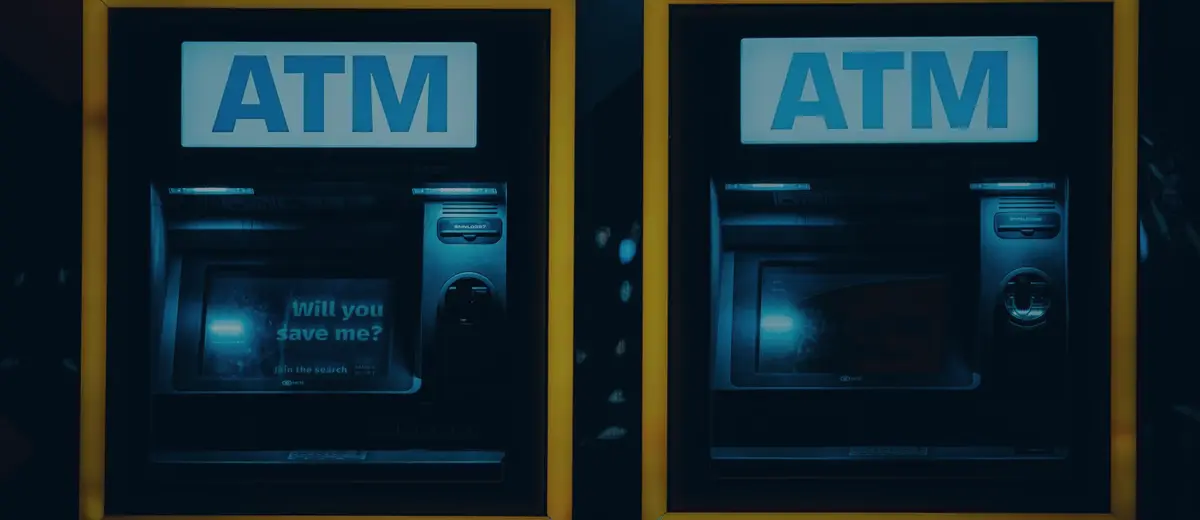 Two lit ATMs set into a dark wall at night.
