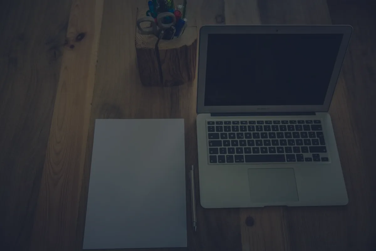 A dark desk with a laptop and paperwork, representing how to do your taxes.