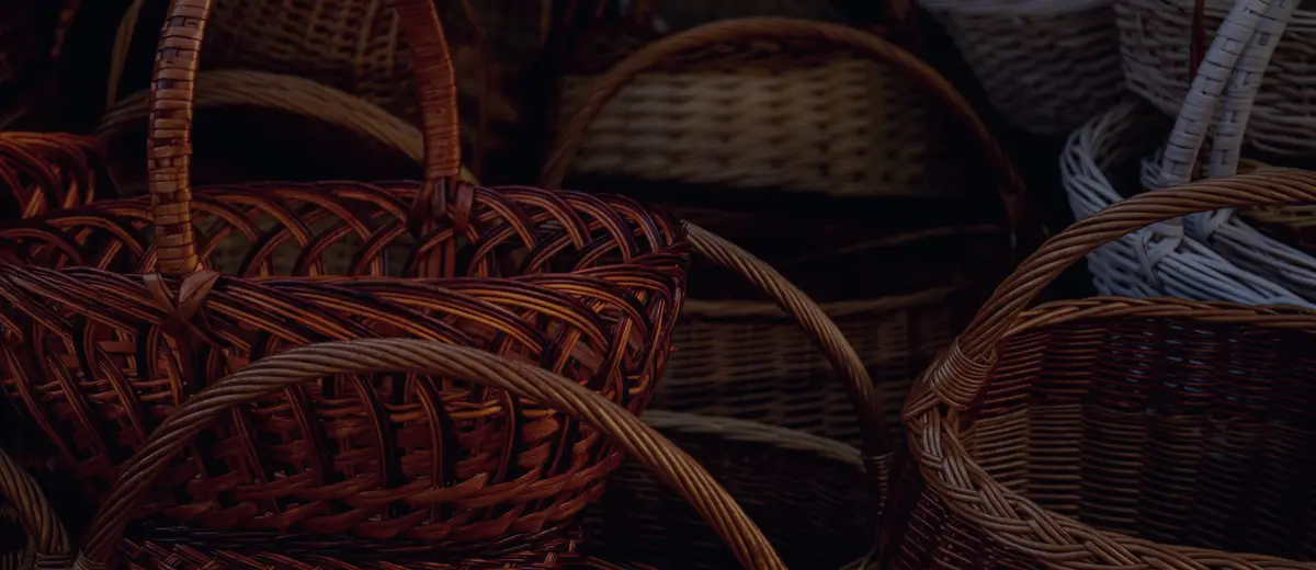 Dozens of woven baskets piled together in low light.