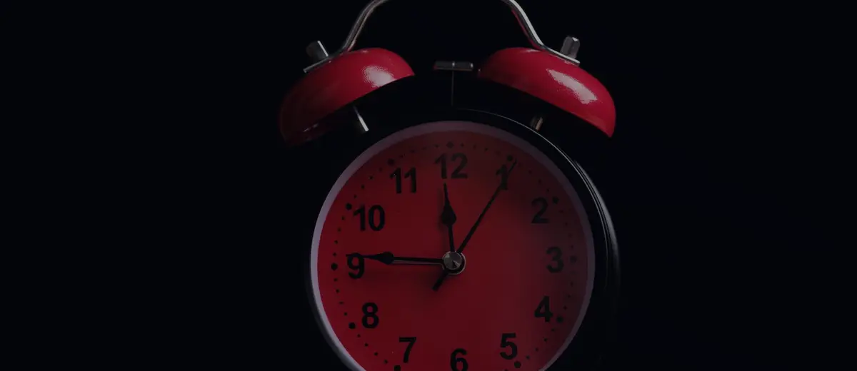 A red alarm clock against a black background.