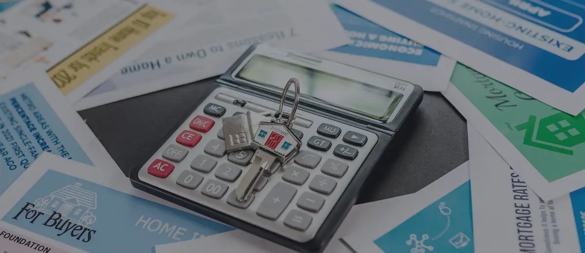 A calculator and house keys on home-buying flyers.