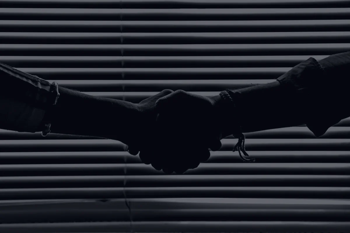 A handshake silhouette in dark light, representing negotiating with creditors.