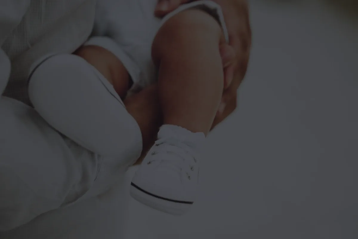 Tiny baby shoes in soft dark light, representing a new baby financial checklist.