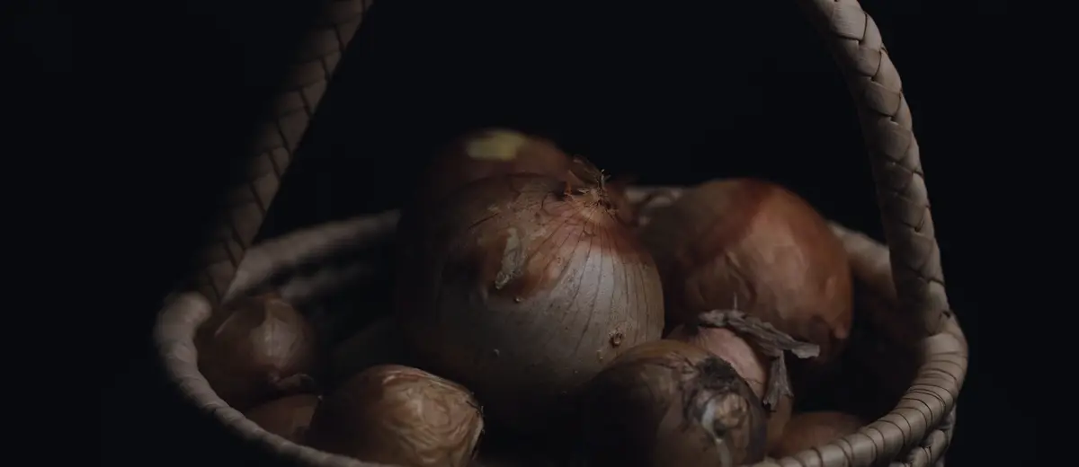 A wicker basket of onions on a dark background: the CPI prices an average basket, and every household fills its own differently.