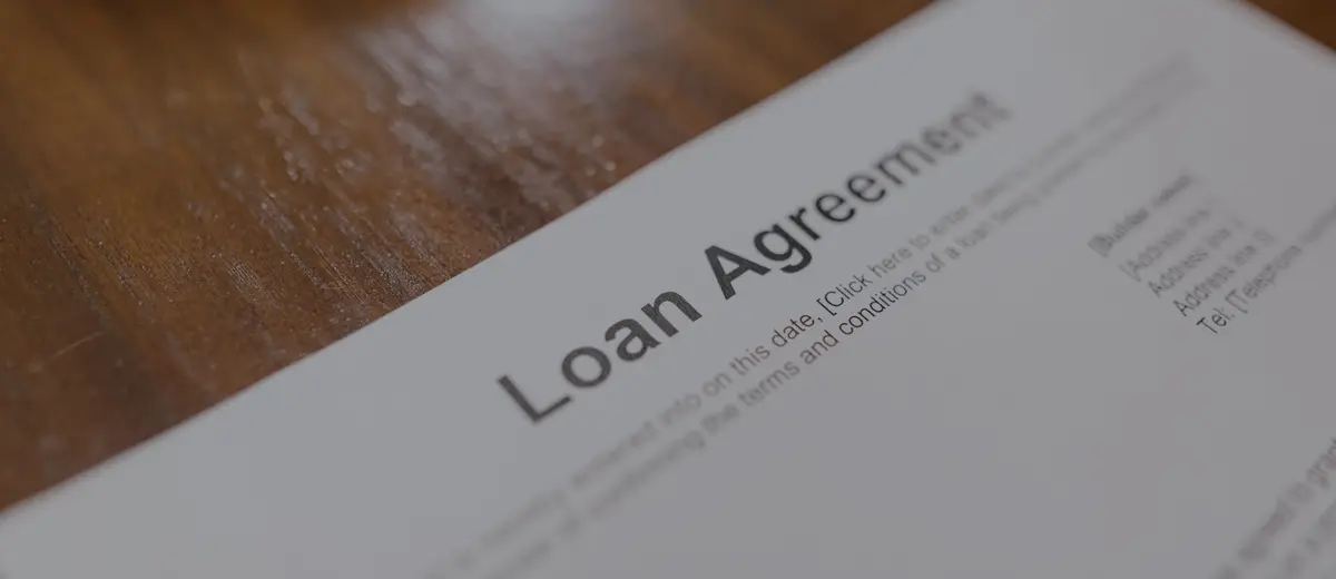 A printed loan agreement on a wooden table.