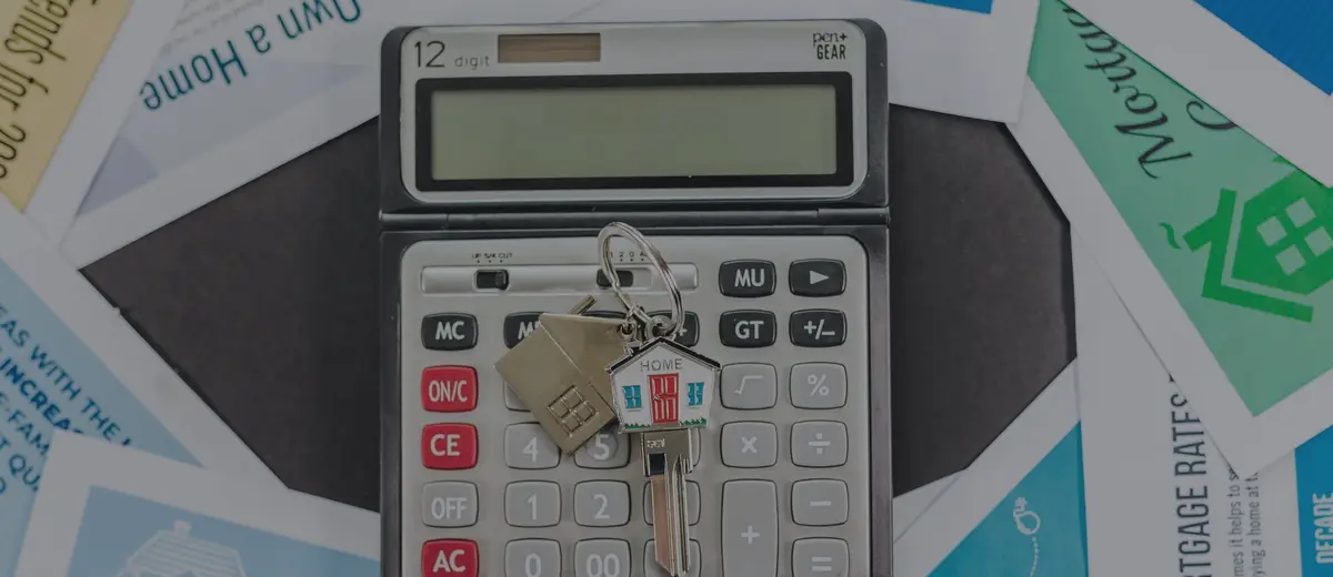 A calculator and house keys on home-buying flyers.