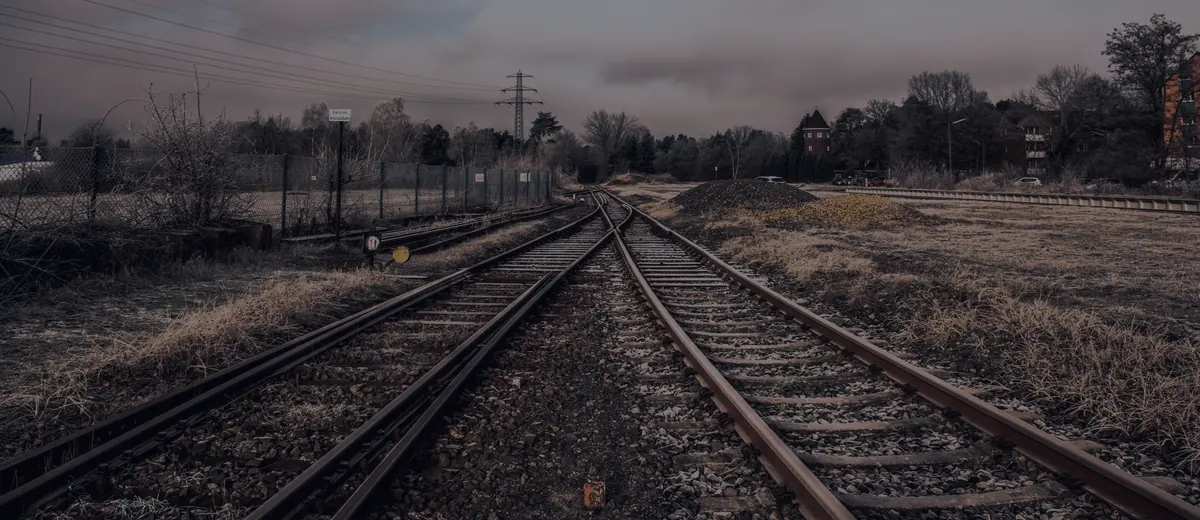 Railway tracks splitting at a switch under a dark evening sky.