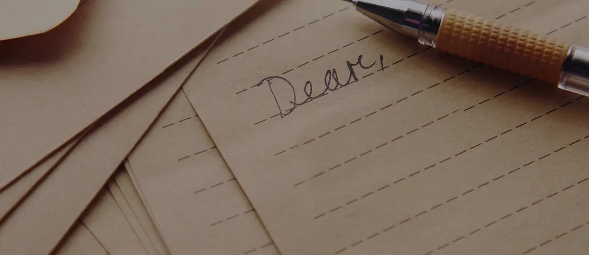 A letter beginning 'Dear' with a pen resting on lined paper.