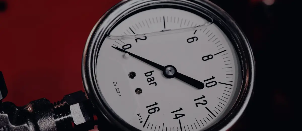 A pressure gauge with its needle past 10 on a dark red background.