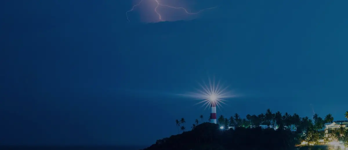 A lighthouse beam at night with lightning over the sea.