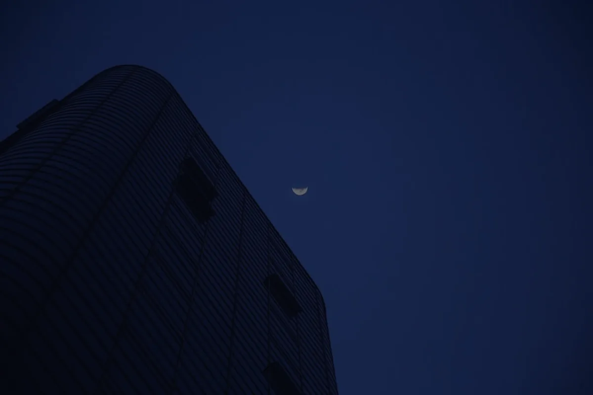 A modern multi-story building lit blue at dusk, representing real estate investment trusts.