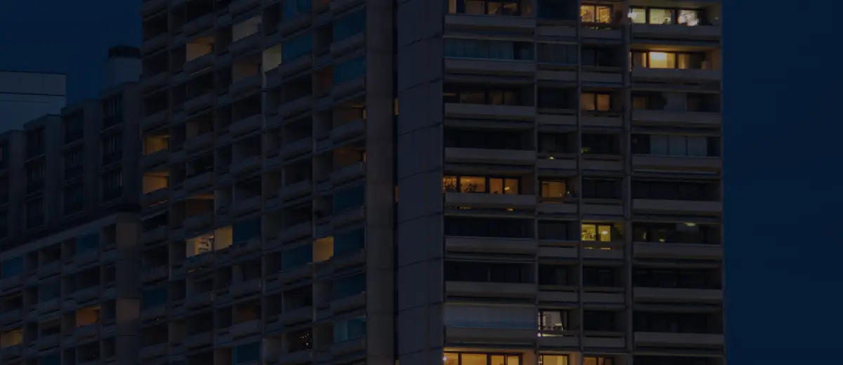 Apartment buildings with lit windows at dusk.