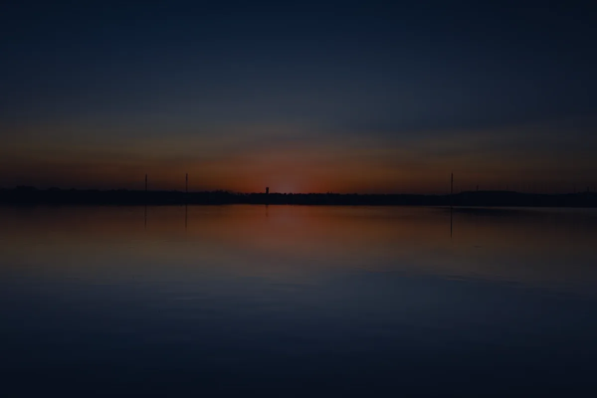 A calm sunrise over dark water, representing the right timing for a Roth conversion.