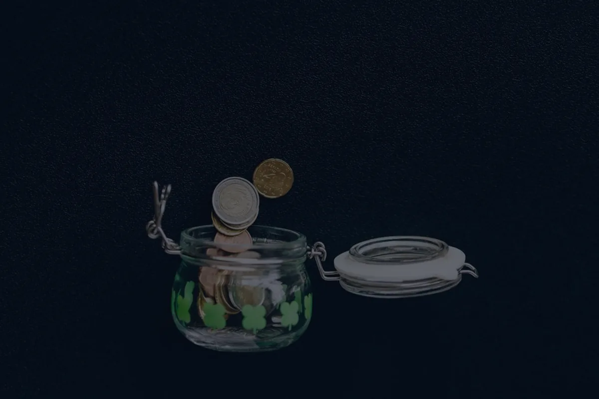 Coins in a glass jar on dark, representing sinking funds set aside for goals.