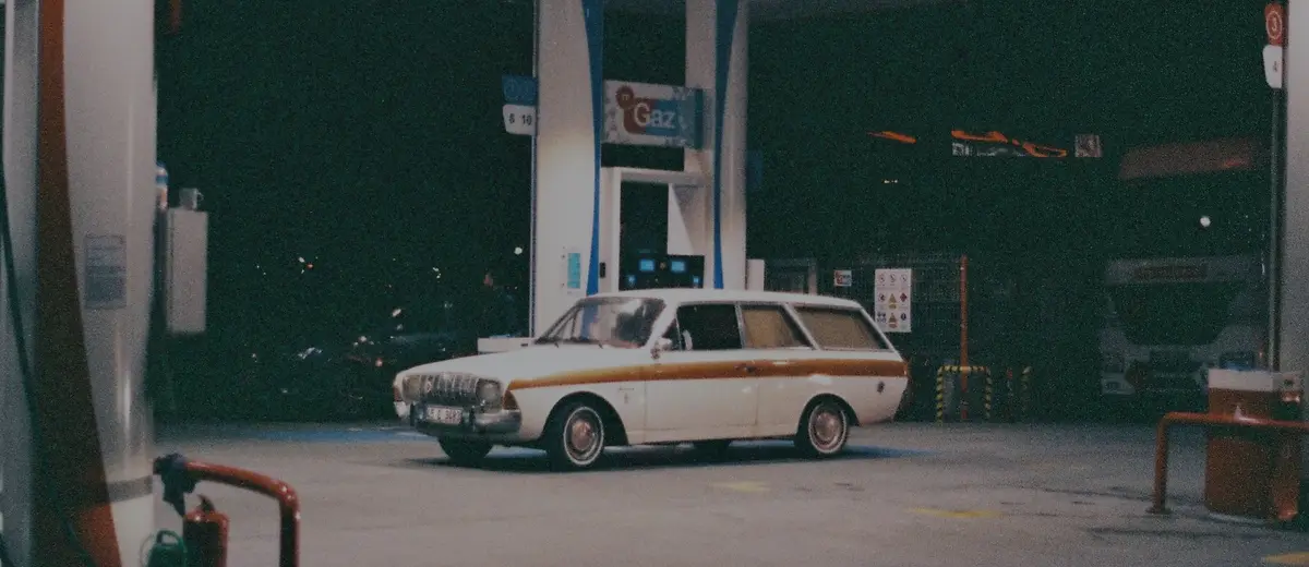 A vintage station wagon at a gas station at night.