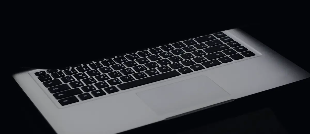 An open laptop glowing in a dark room.