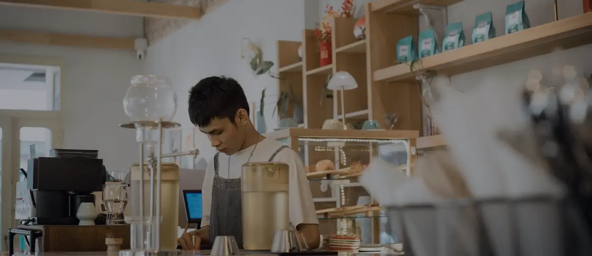 A young barista working behind a café counter.