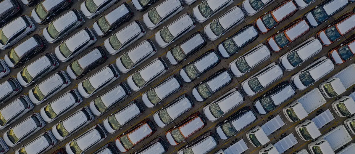 An aerial view of rows of new cars parked in a lot.