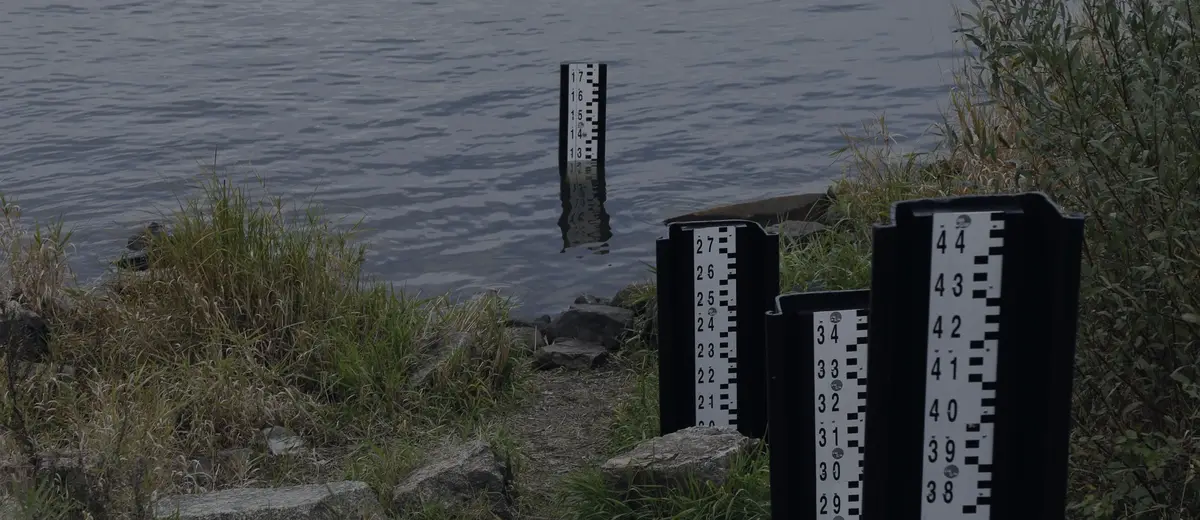 Water-level gauges standing at the edge of a river.