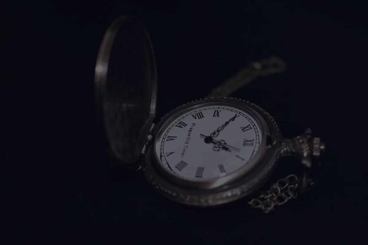 A vintage pocket watch on a dark background, representing the timing of claiming Social Security.