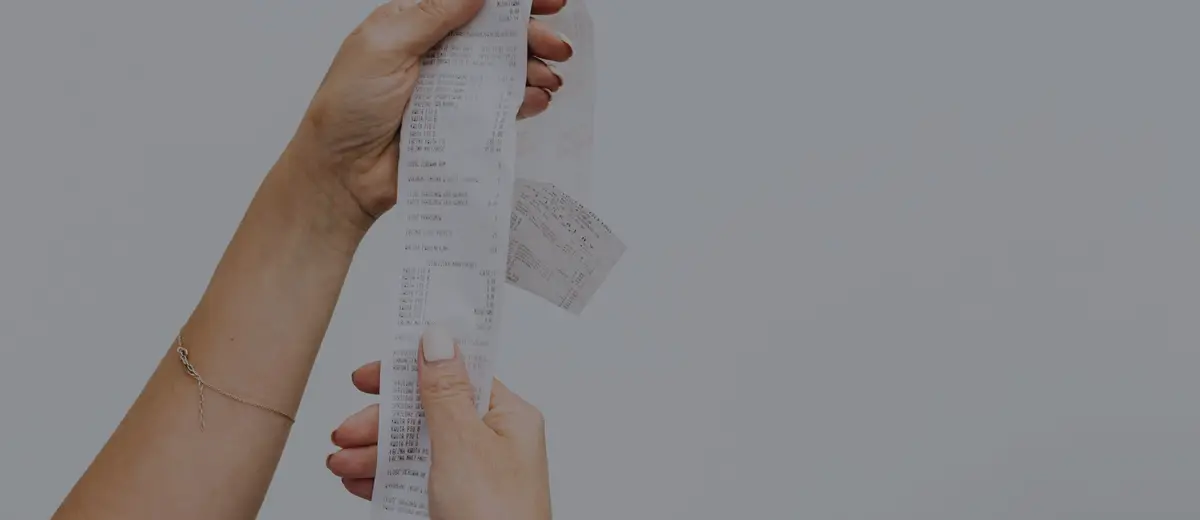 Two hands holding up a long shopping receipt.