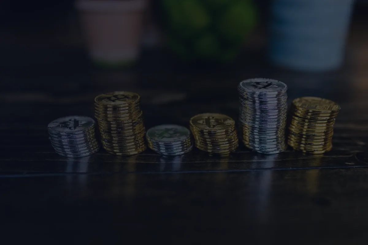 Ascending stacks of gold and silver coins on a dark surface, representing a rising personal savings rate over time.